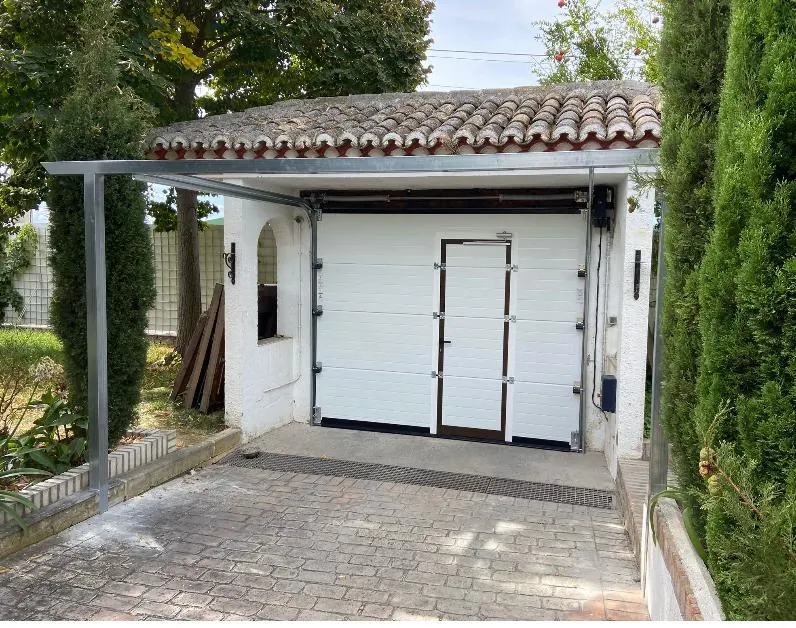 Puerta seccional blanca en el garaje de un chalet