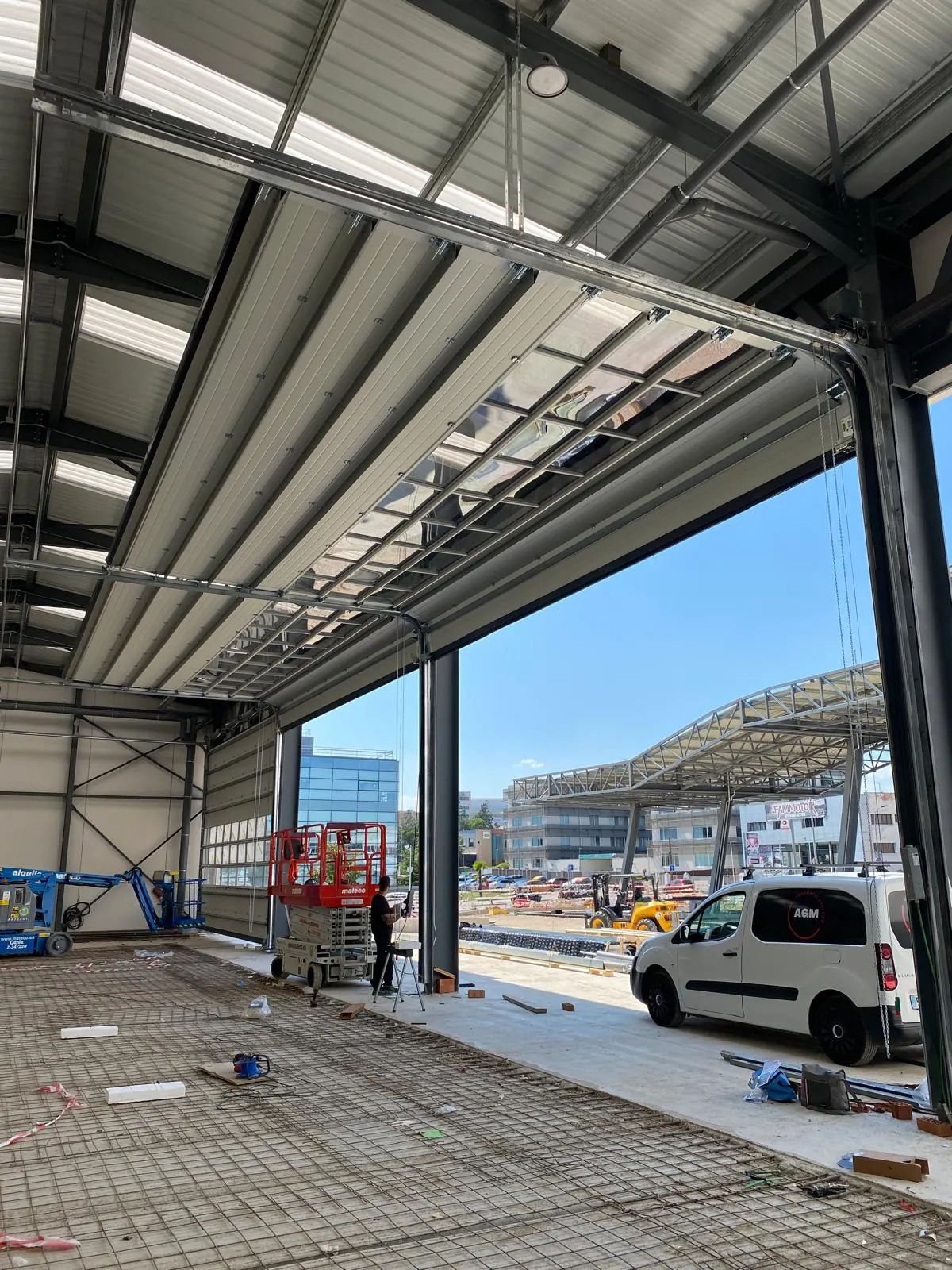 Puerta industrial abierta en una nave con paso de maquinaria
